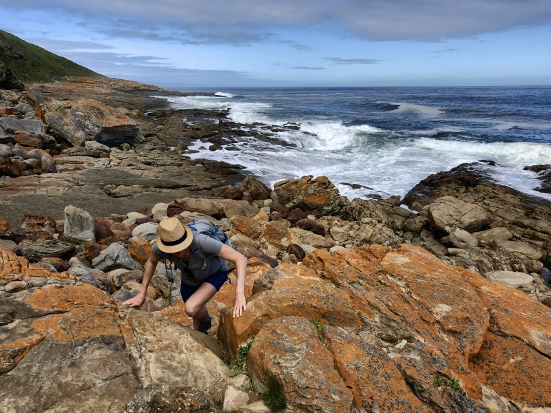 Frau beim Klettern auf Robberg Island, Südafrika