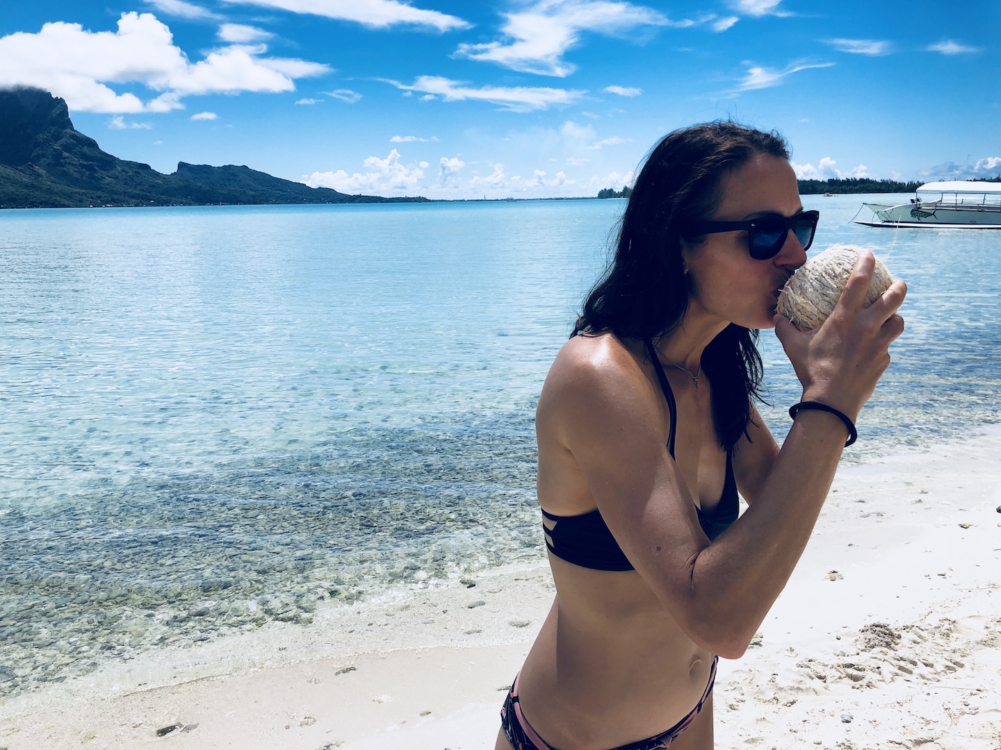 Frau trinkt Kokoswasser aus Kokosnuss auf Bora Bora